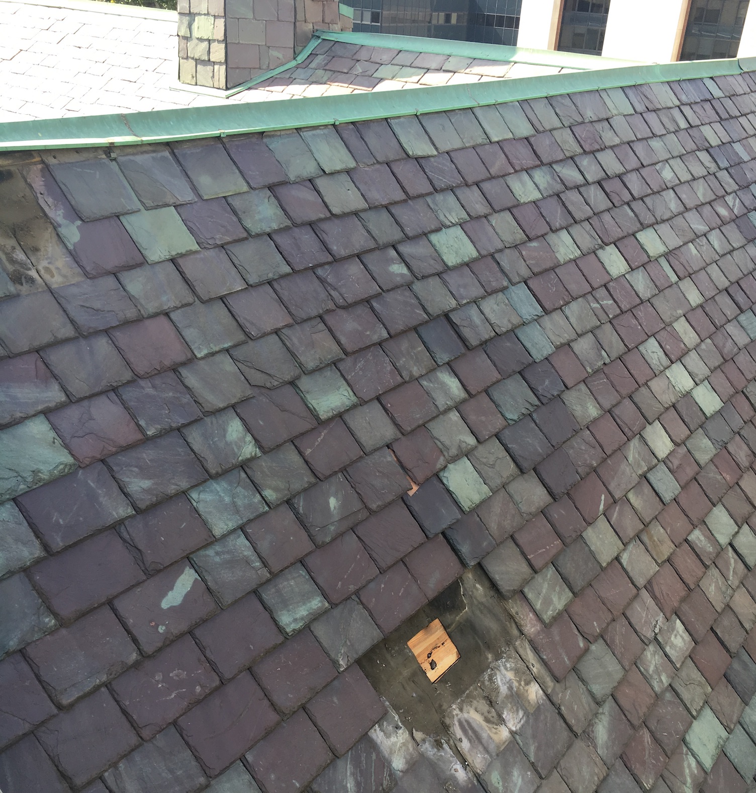 Detail of slate roof tiles, with one removed for exploration by renovation team.