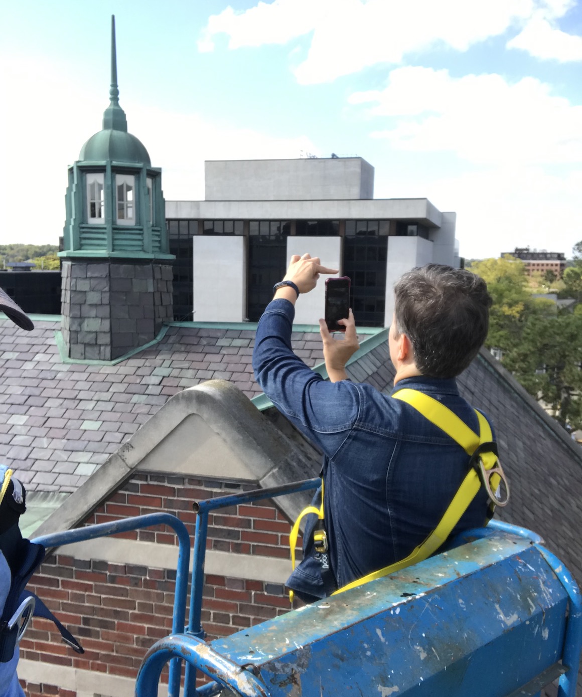 General Manager Kathy Ciesinski photographs the slate tiles from a cherry-picker prior to roof renovations. 